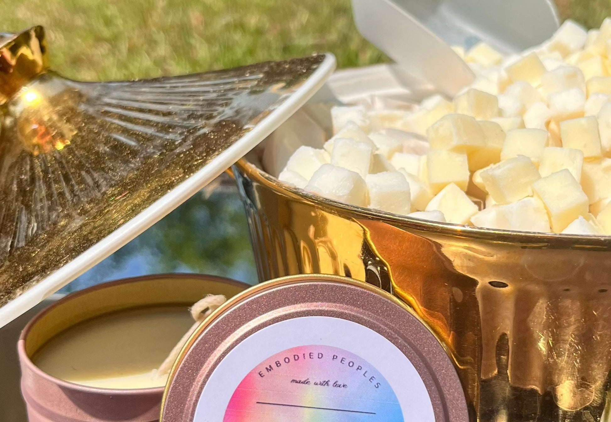 Cubies (small cube of body butter) pictured in an ornate golden holder alongside the  massage candle counterpart